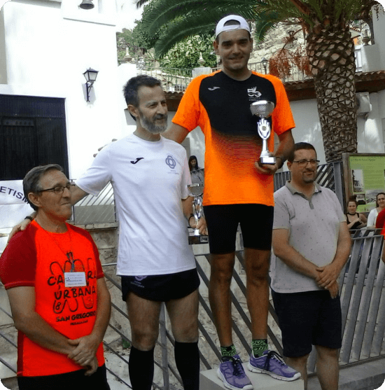 Personas recibiendo un premio en un podio vestidos con ropa deportiva.