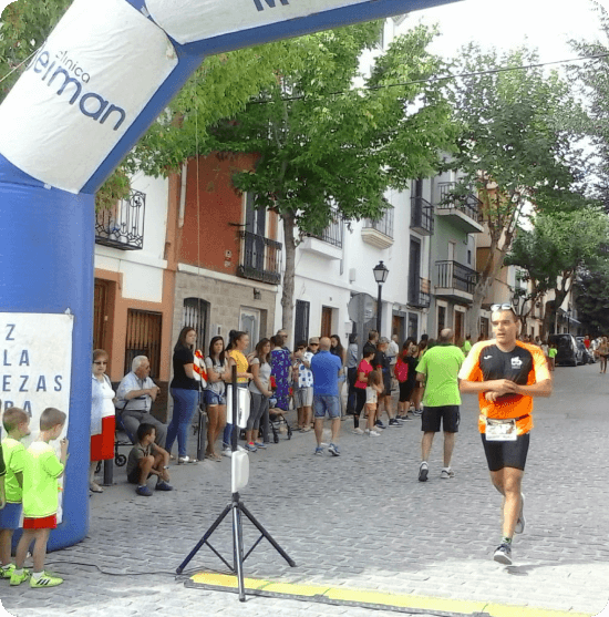 Línea de meta en una carrera con un corredor llegando a ella.